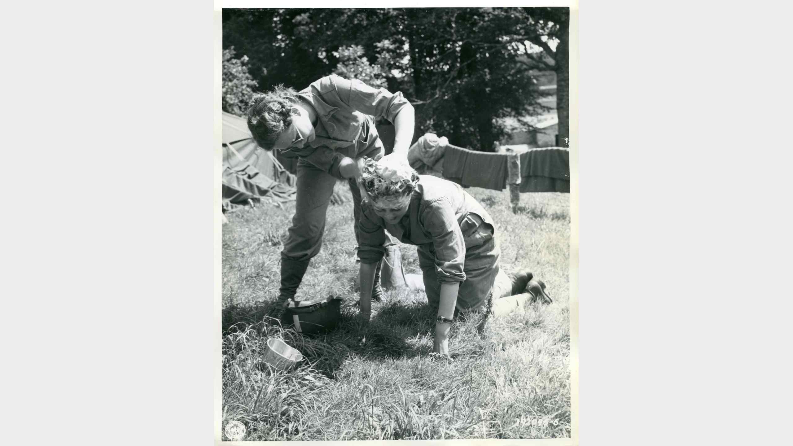 Two WACs in Normandy wash their hair inside a steel helmet Two WACs in Normandy wash their hair inside a steel helmet